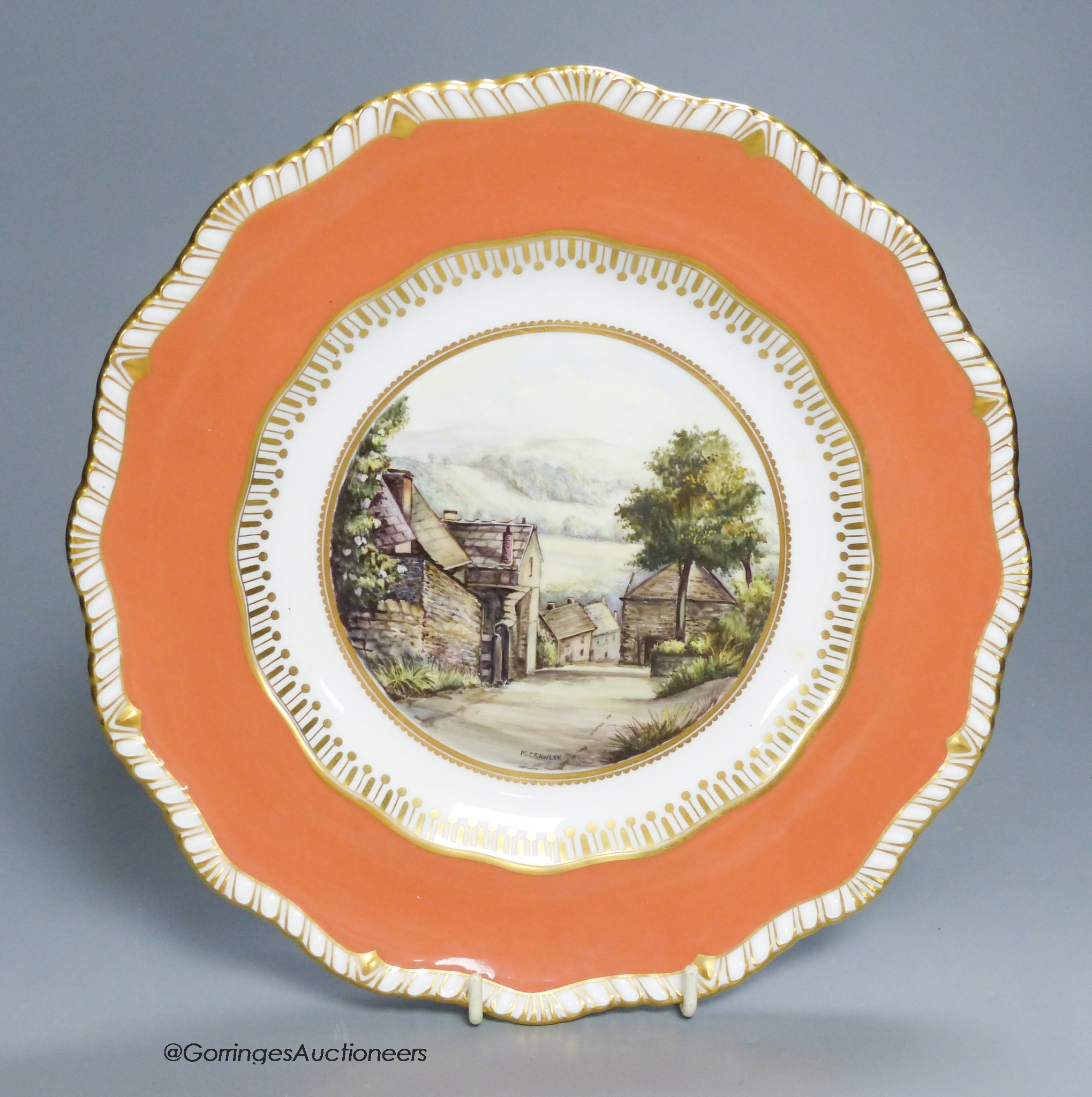 A Royal Crown Derby plate painted with a view of Stoney Middleton, Derbyshire under a burnt orange border by M. Crawley, signed, 23cm diameter